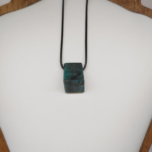 Necklace with a green stone pendant on a white cushion