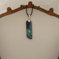 Necklace with a green stone pendant on a neutral background