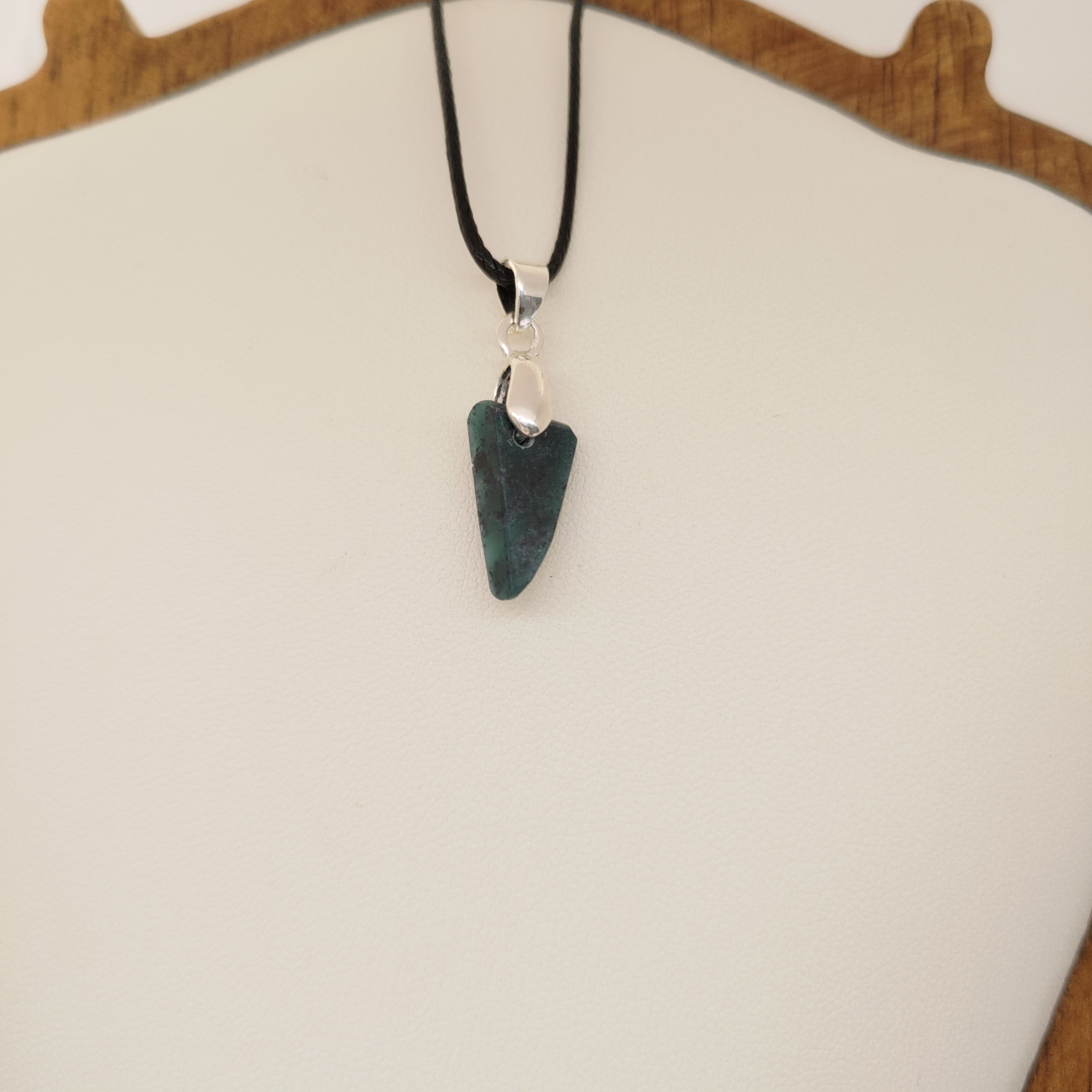 Necklace with a green stone pendant on a white surface